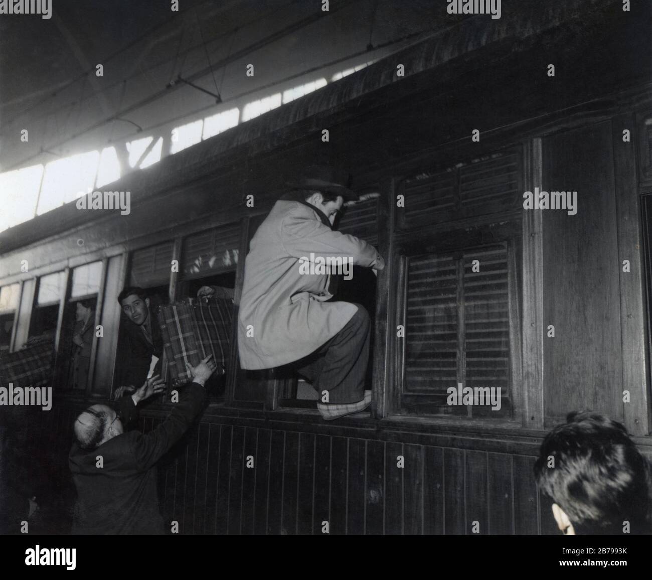 Barcelona. Estación de Francia. Emigración. Pasajeros encaramados a una ventanilla del tren e introduziendo el equipaje. Año 1954. Stockfoto