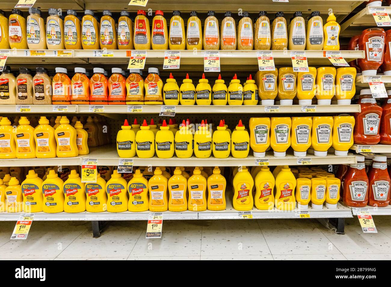 Verschiedene Marken gelber Senfsoßenflaschen, die in den Regalen des condiments Gang im Supermarkt voll bevorratet sind Stockfoto