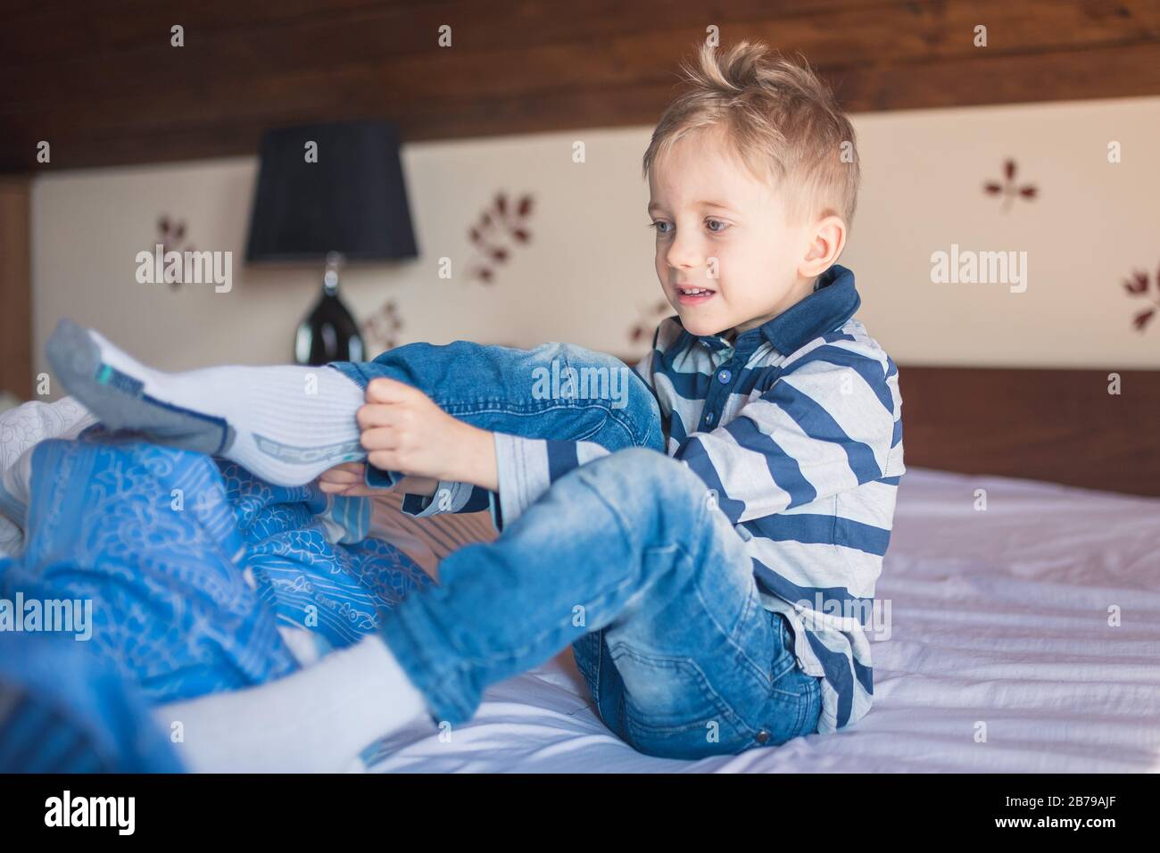Fünf Jahre alter Junge kleidet morgens seine Socken auf dem Bett Stockfoto
