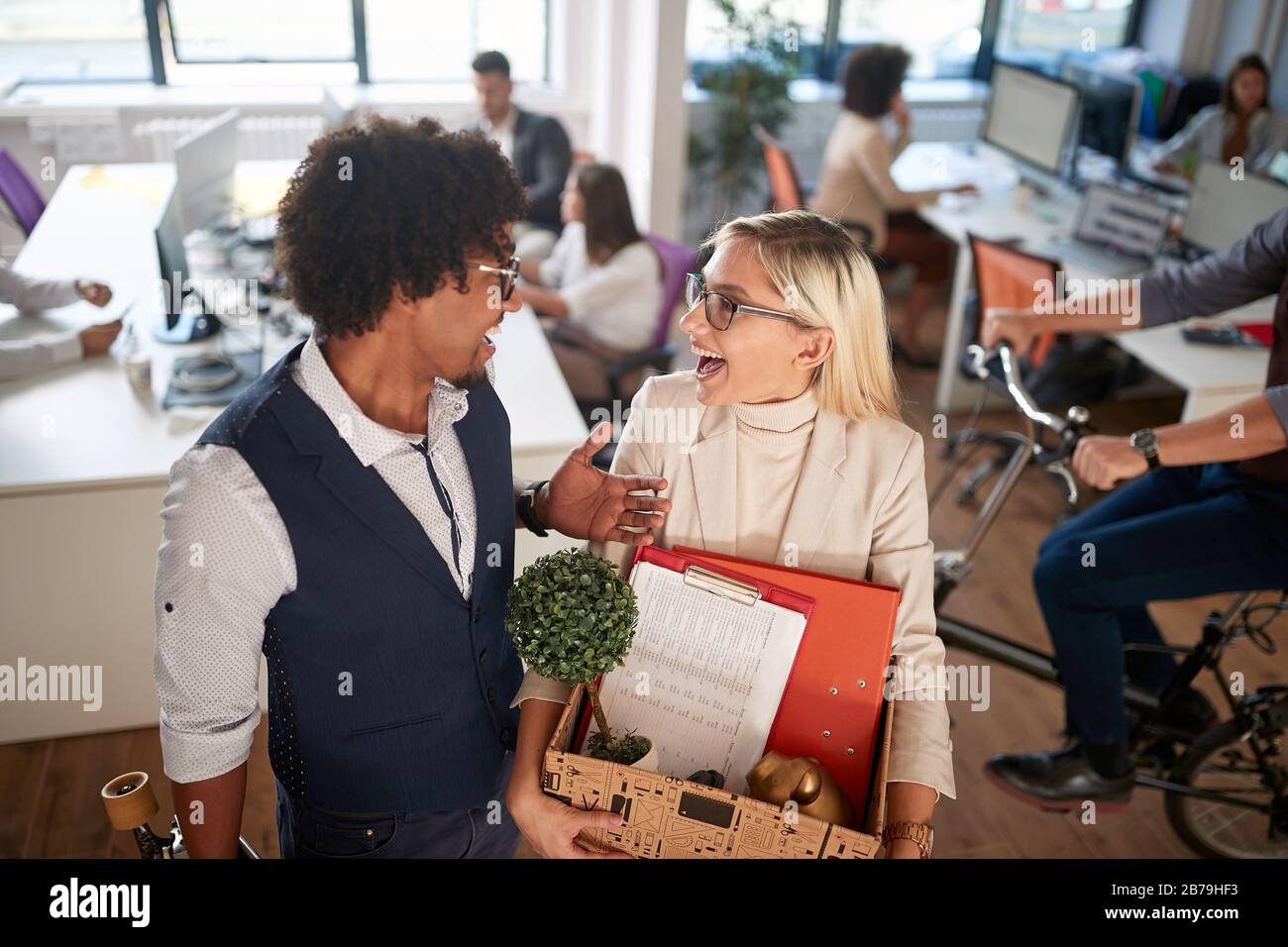 Lächelnde junge Frau, die mit Kollegen in einem neuen Büro umherzieht. Stockfoto