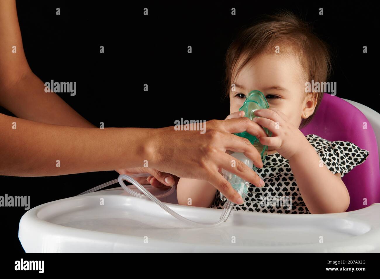 Kleines Baby mit Inhalationsmaske auf dem Gesicht isoliert auf schwarzem Hintergrund Stockfoto