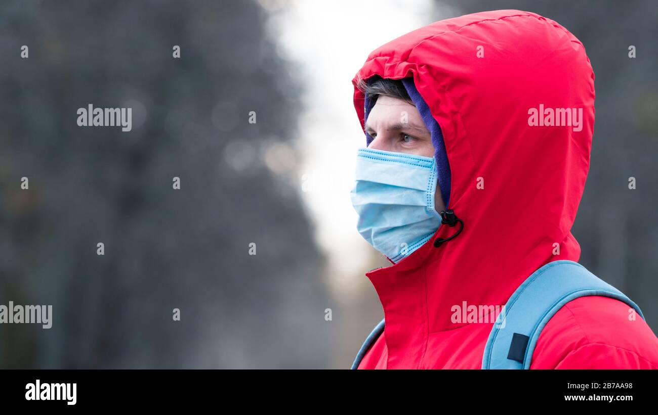 Nahaufnahme Portrait junger europäer Mann in schützender, medizinischer Gesichtsmaske, die draußen spazieren geht. Neues Coronavirus (COVID-19). Konzept der Gesundheitsversorgung Stockfoto