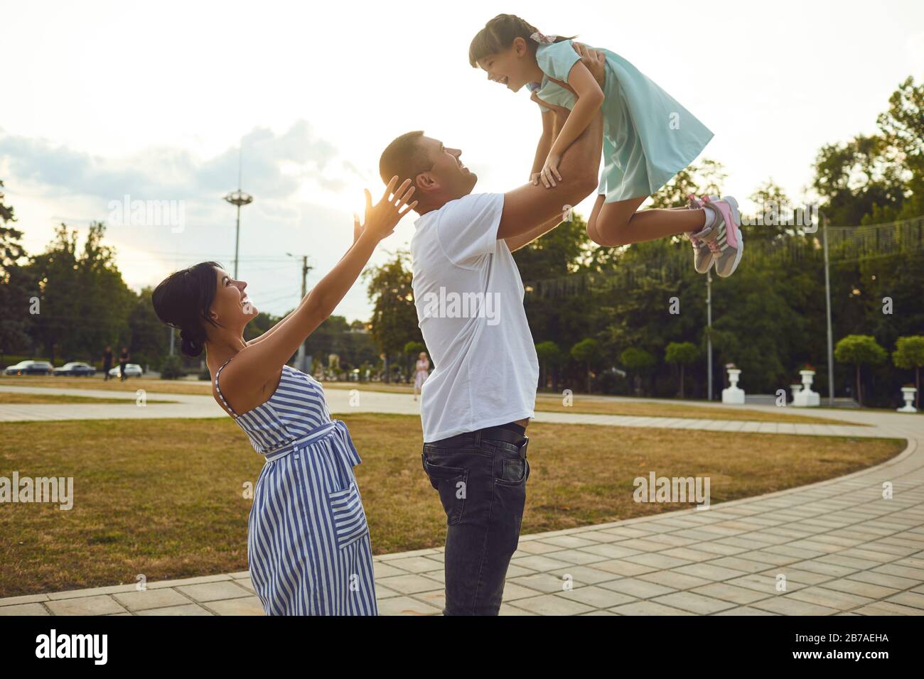 Vater und Mutter, die Spaß haben, werfen eine Tochter auf die Straße Stockfoto