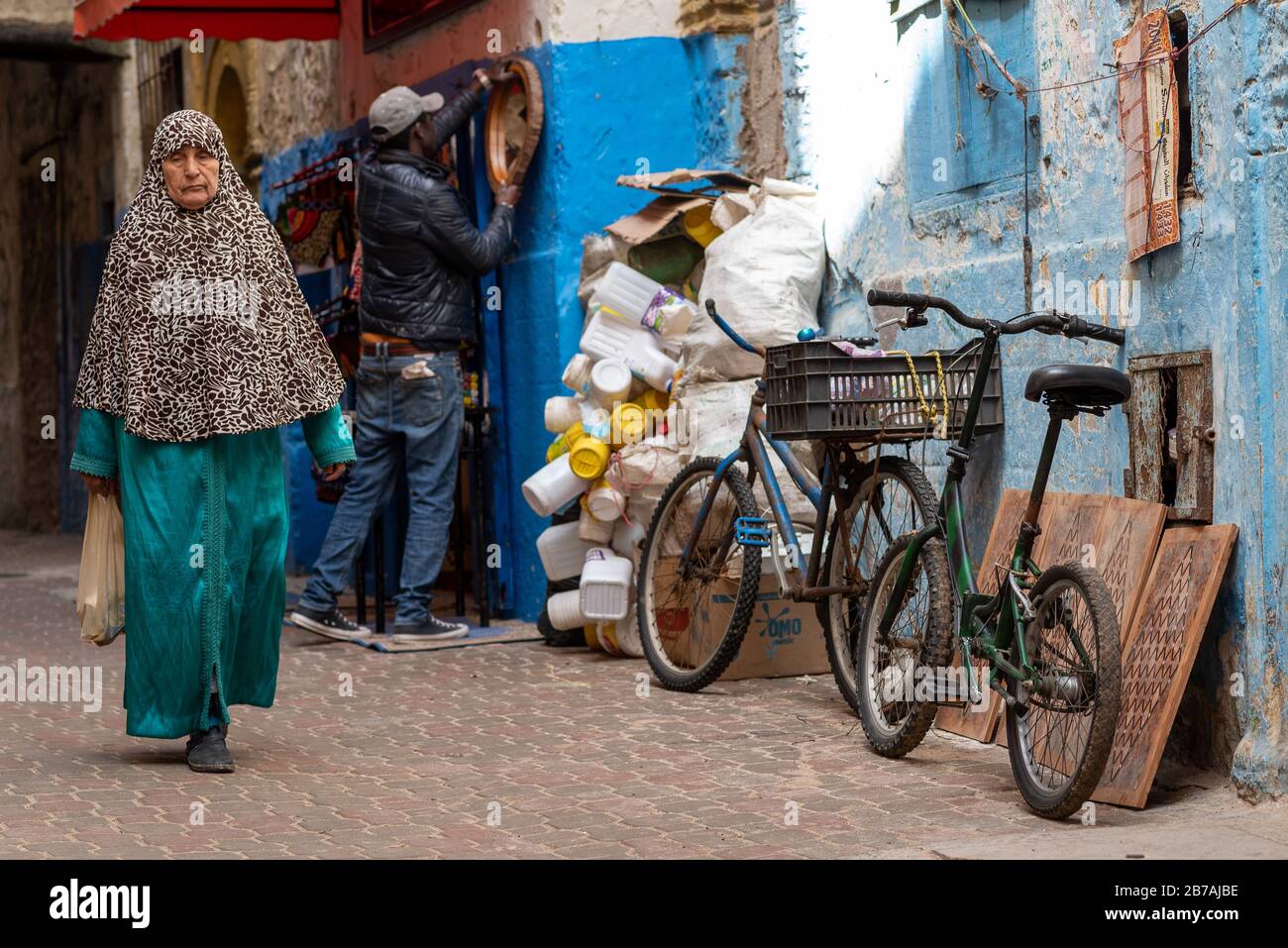 Street-Szene mit lokaler Dame mit Geschäften und Fahrrädern - Essaouira, Marokko Stockfoto