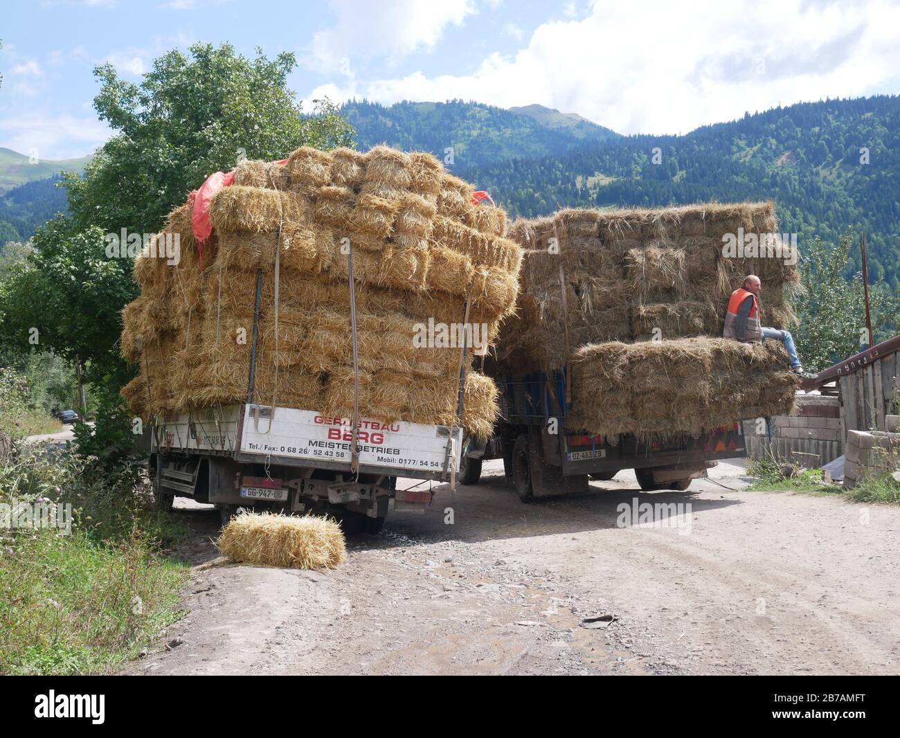 Mit Heu beladene LKWs überholen sich auf der Bergstraße der kiesigen Wildnis im Land Georgia Stockfoto