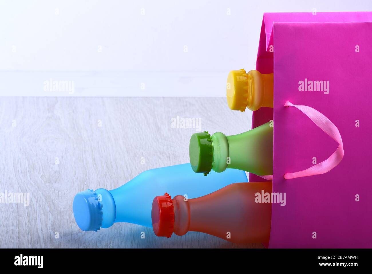 Energy trinkt Behälter mit verschiedenen Geschmacksrichtungen. Satz Flaschen in verschiedenen Farben in pinkfarbener Verpackung. Einkaufstasche mit bunten alkoholfreien Getränken auf grauem Hintergrund. Farbauswahl und Container-Konzept Stockfoto