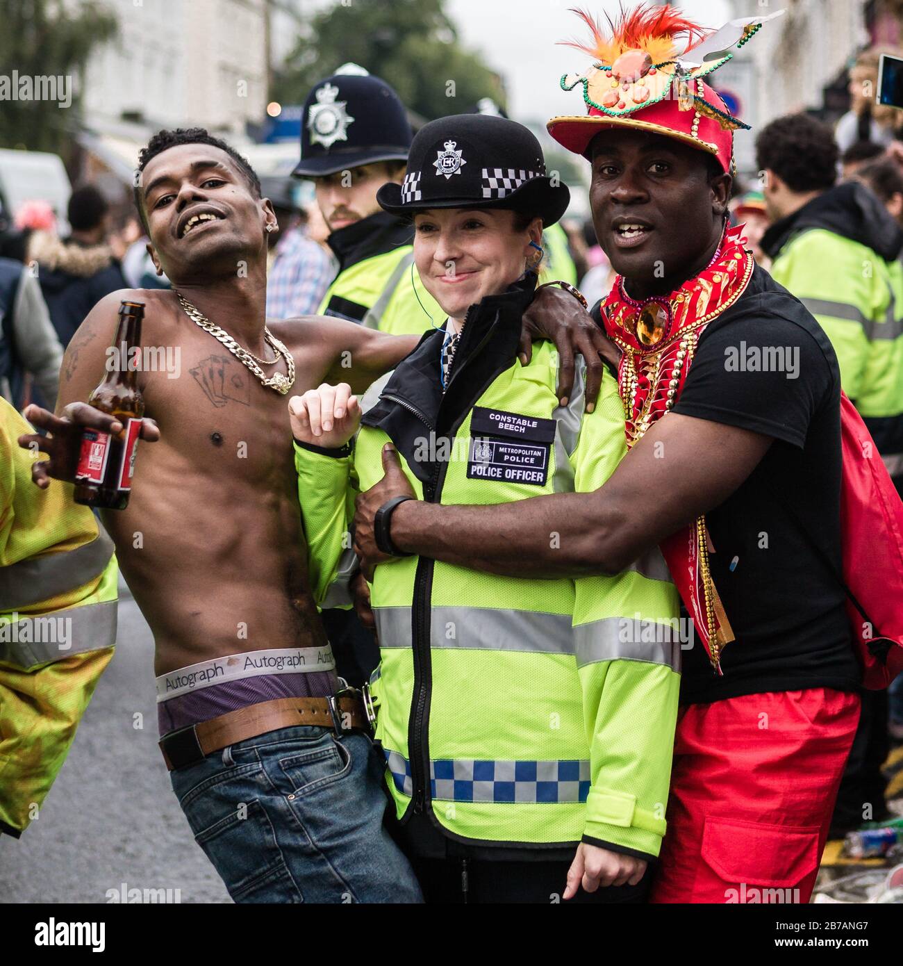 Zwei Enthüller posieren für ein frech Foto mit einem Polizisten im Nottinghill Carnival in London. Stockfoto