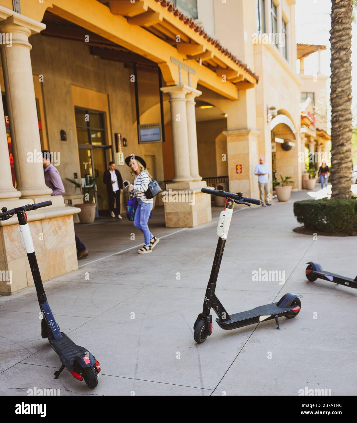 Elektro-Roller werden auf dem Bürgersteig mit Menschen in der Gegend der Scottsdale Waterfront mit Eigentumswohnungen, Restaurants und Einkaufsmöglichkeiten, AZ, planlos geparkt Stockfoto