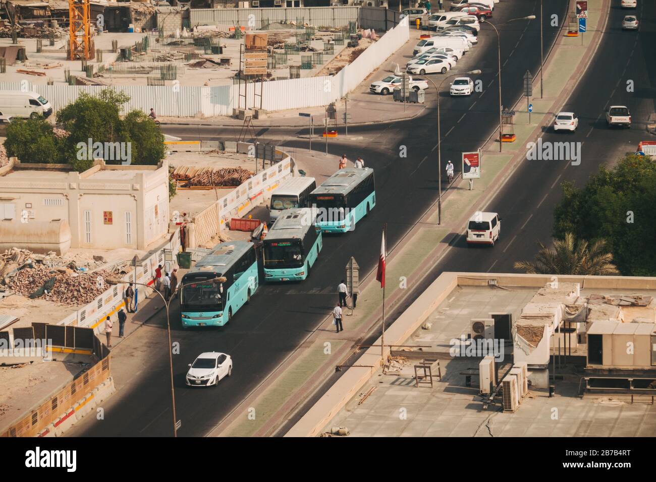 Markante türkisfarbene Karwa-Busse der öffentlichen Verkehrsmittel in Doha, Katar, fahren an einer Bushaltestelle auf der Straßenseite in der Stadt vorbei Stockfoto