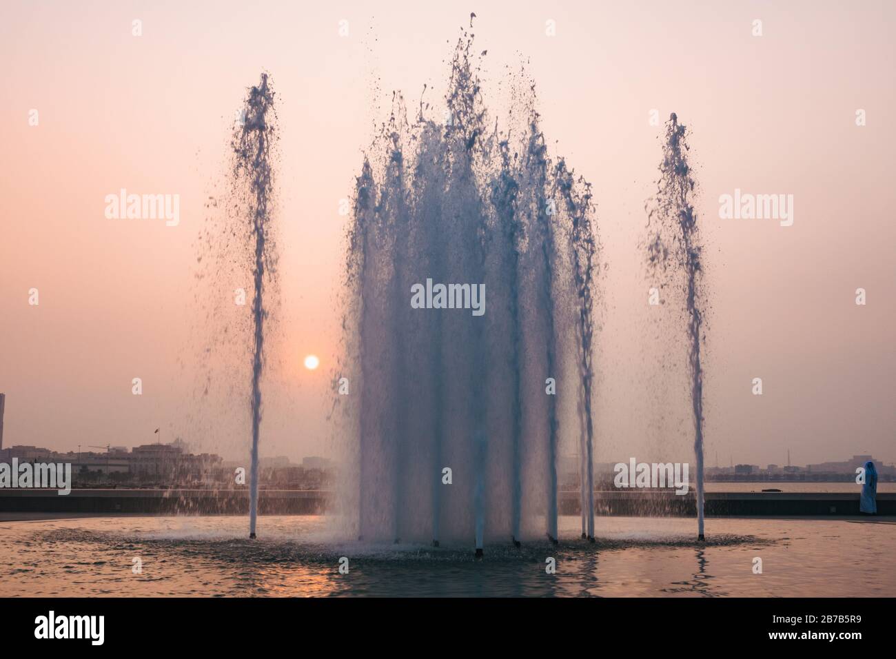 Die Sonne geht hinter einem Wasserbrunnen vor dem Museum für Islamische Kunst in Doha, Katar, unter Stockfoto
