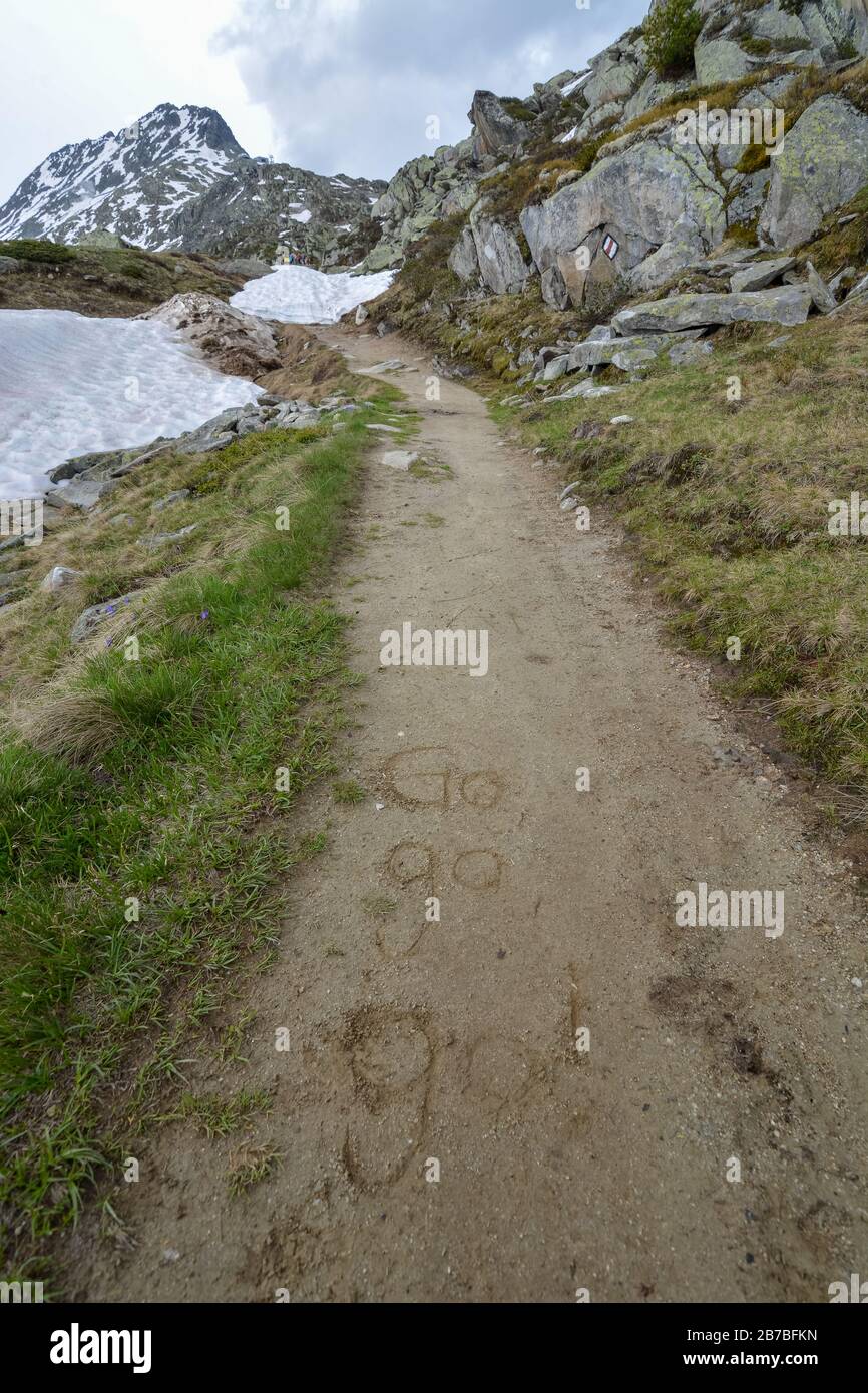 Ein Weg mit den Worten Go Go geht an einem sonnigen Tag in den Schlamm nahe dem Aletschgletscher in den Schweizer alpen Stockfoto