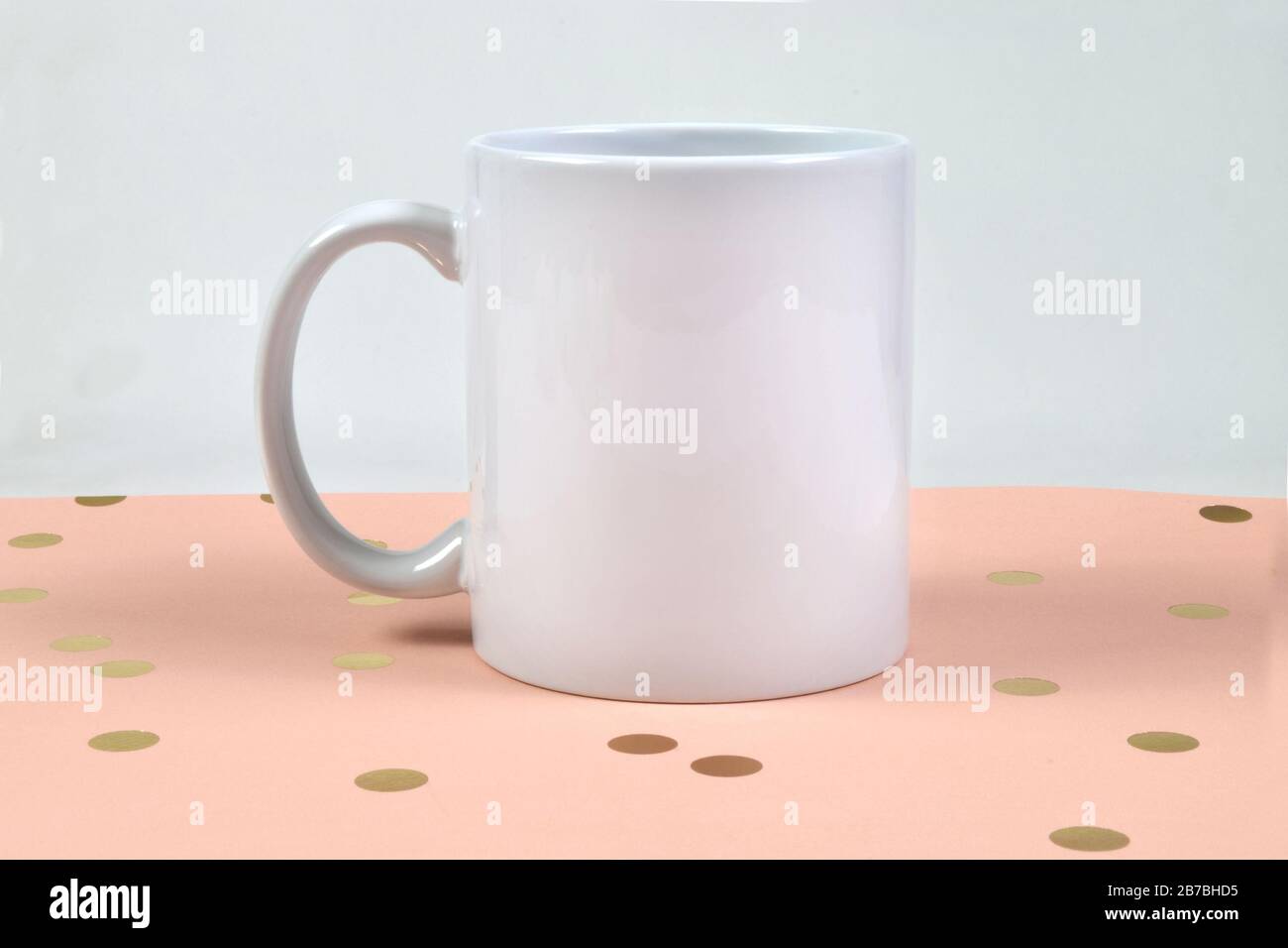 Dieser Mockup mit Kaffeetasse verfügt über einen weißen Becher mit 11 Unzen, der auf einem schönen Hintergrund mit pinkfarbenen und goldenen Punkten ruht. Ideal für Ostern, Frühling, Babyduschen und mehr. Stockfoto