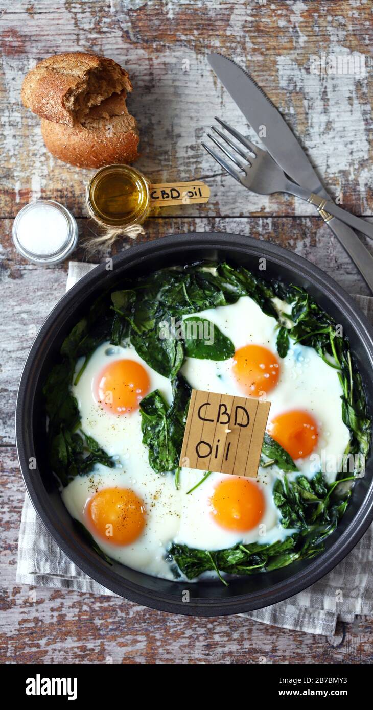 Selektiver Fokus. Die Aufschrift cbd Oil in Food. Spinateier mit Cannabisöl. CDB-Verwendung des Ölkonzepts. Stockfoto