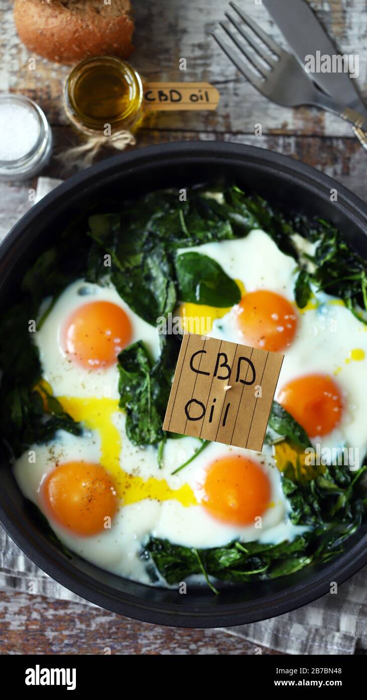 Selektiver Fokus. Die Aufschrift cbd Oil in Food. Spinateier mit Cannabisöl. CDB-Verwendung des Ölkonzepts. Stockfoto