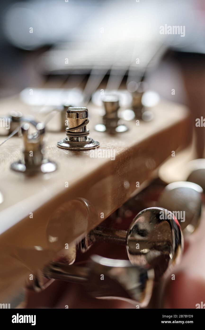 Saite wunde auf einem Pflock, dicht oben, auf dem Kopfstock einer alten Holzgitarre. Tuning-Mechanismen für gestringte Instrumente. Stockfoto