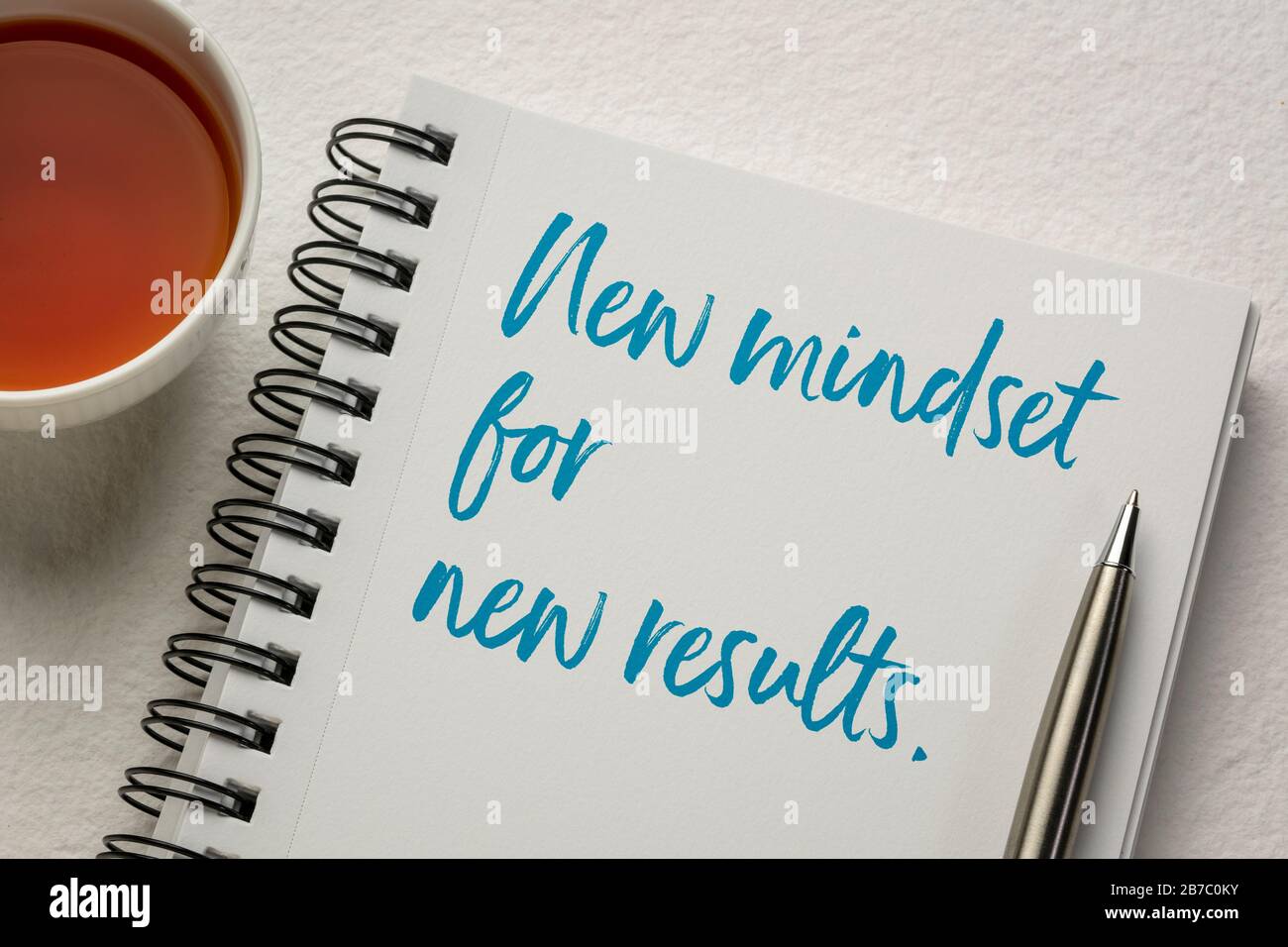 Neue Denkweise und neues Ergebniskonzept - Handschrift in einem Skizzenbuch mit einer Tasse Tee. Unternehmen, Kreativität und persönliche Entwicklung. Stockfoto