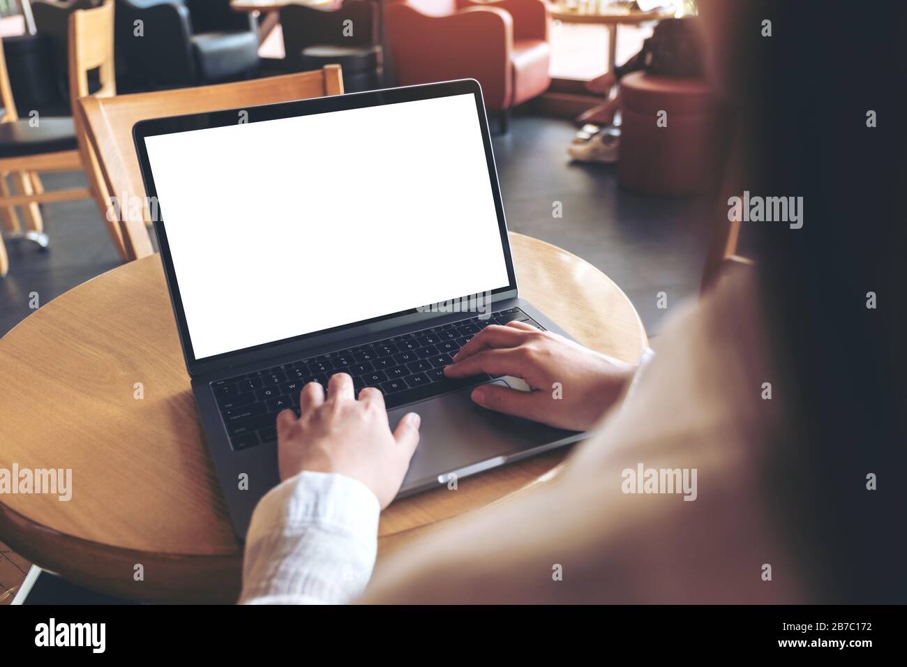 Verspottes Bild von Geschäftsfrau, die in einem Café auf einem Laptop mit leerem weißem Desktop-Bildschirm tippt und tippt Stockfoto