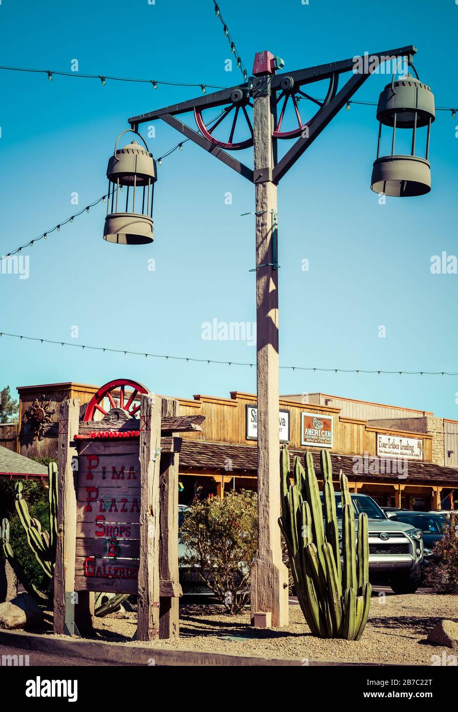 Ein altes Westthema mit alten Straßenlaternen und Teilen mit Wagenrädern mit Beschilderung für die Pima Plaza Geschäfte und Galerien in der Altstadt von Scottsdale, AZ Stockfoto