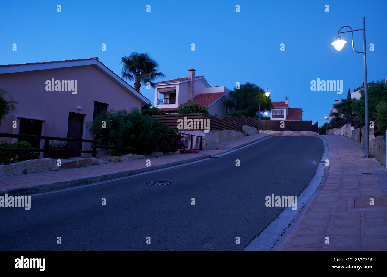 Der Blick auf die Straße mit der Linie der Wohnhäuser des Dorfes Pissouri im Abendlicht. Bezirk Limassol. Zypern Stockfoto