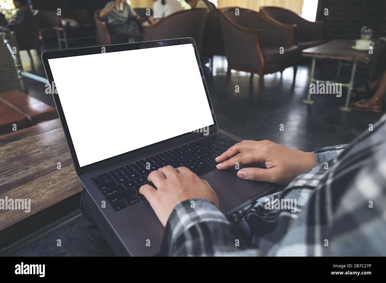Verspottes Bild von Geschäftsleuten, die auf einem Laptop mit leerem weißem Desktop-Bildschirm unterwegs sind, während sie auf einem Stuhl sitzen Stockfoto