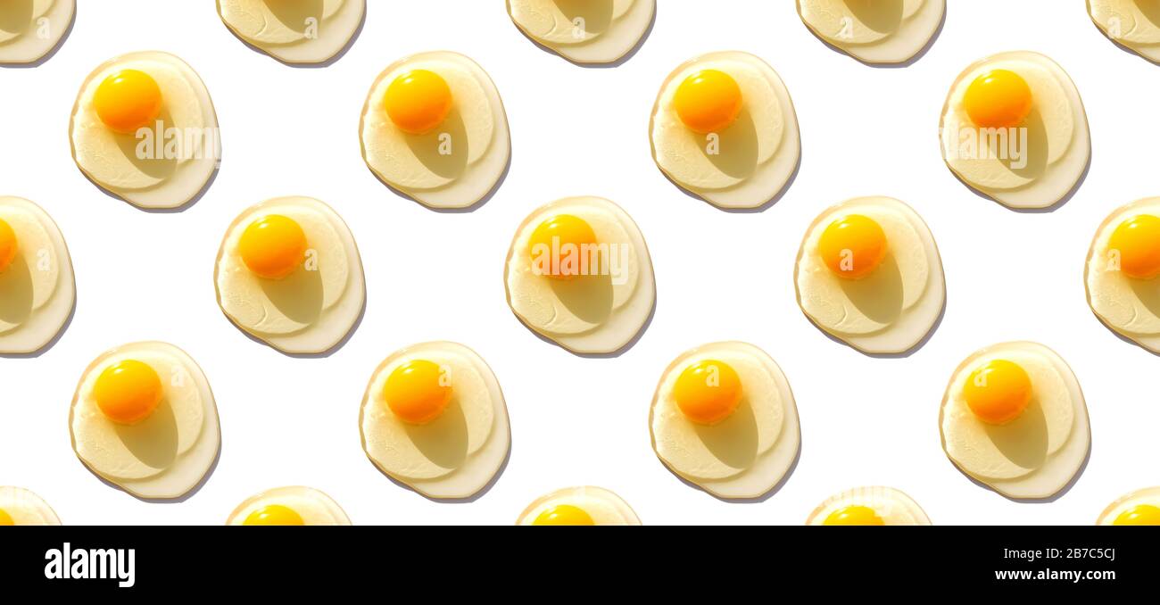 Kreatives minimalistisches Muster mit rohen Eiern mit Eigelb auf weißem Hintergrund. Stockfoto