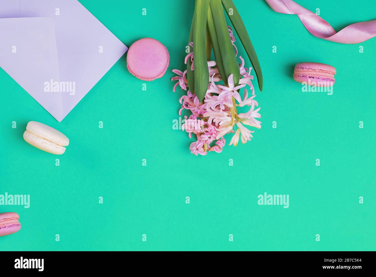 Flache Feder-Laienzusammensetzung mit Makronen und rosafarbenen Hyazinthblüten Stockfoto