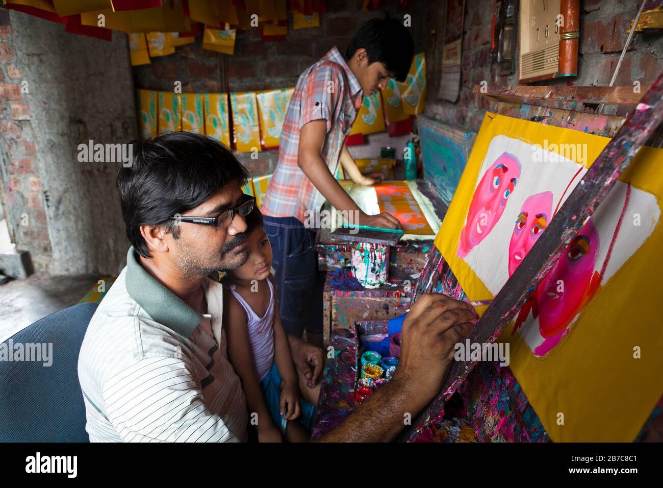 Proshanto Kumar das, Sohn von Raj Kumar das, am besten bekannt als RK das, einer der Rikschah-Künstler der ersten Generation in Bangladesch, ist mit dem Malen einer Rikschah-Kunst beschäftigt, während ihm seine Freude am 3. Mai 2012 in seinem Studio in der Hauptstadt Dhaka hilft. Die Rikscha-Kunst ist eine Form von Popkunst, die unsere urbane Kultur und Folklore von Bangladesch darstellt. Rickschas wurden erstmals in Bangladesch in den 1930er Jahren aus Japan eingeführt, wo die dreirädrigen Fahrzeuge als "nintaku" bekannt waren. Die Idee, die beingetriebenen Schmuggelware zu schmücken, ging in Bangladesch in den 1950er Jahren mit der Tradition nach dem einfachen, aber dennoch kolorfen Dorf aus Stockfoto