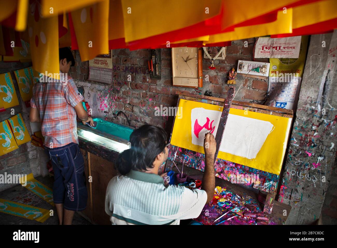 Proshanto Kumar das, Sohn von Raj Kumar das, am besten bekannt als RK das, einer der Rikschah-Künstler der ersten Generation in Bangladesch, ist mit dem Malen einer Rikschah-Kunst beschäftigt, während ihm seine Freude am 8. Mai 2012 in seinem Studio in der Hauptstadt Dhaka hilft. Die Rikscha-Kunst ist eine Form von Popkunst, die unsere urbane Kultur und Folklore von Bangladesch darstellt. Rickschas wurden erstmals in Bangladesch in den 1930er Jahren aus Japan eingeführt, wo die dreirädrigen Fahrzeuge als "nintaku" bekannt waren. Die Idee, die beingetriebenen Schmuggelware zu schmücken, ging in Bangladesch in den 1950er Jahren mit der Tradition nach dem einfachen, aber dennoch kolorfen Dorf aus Stockfoto