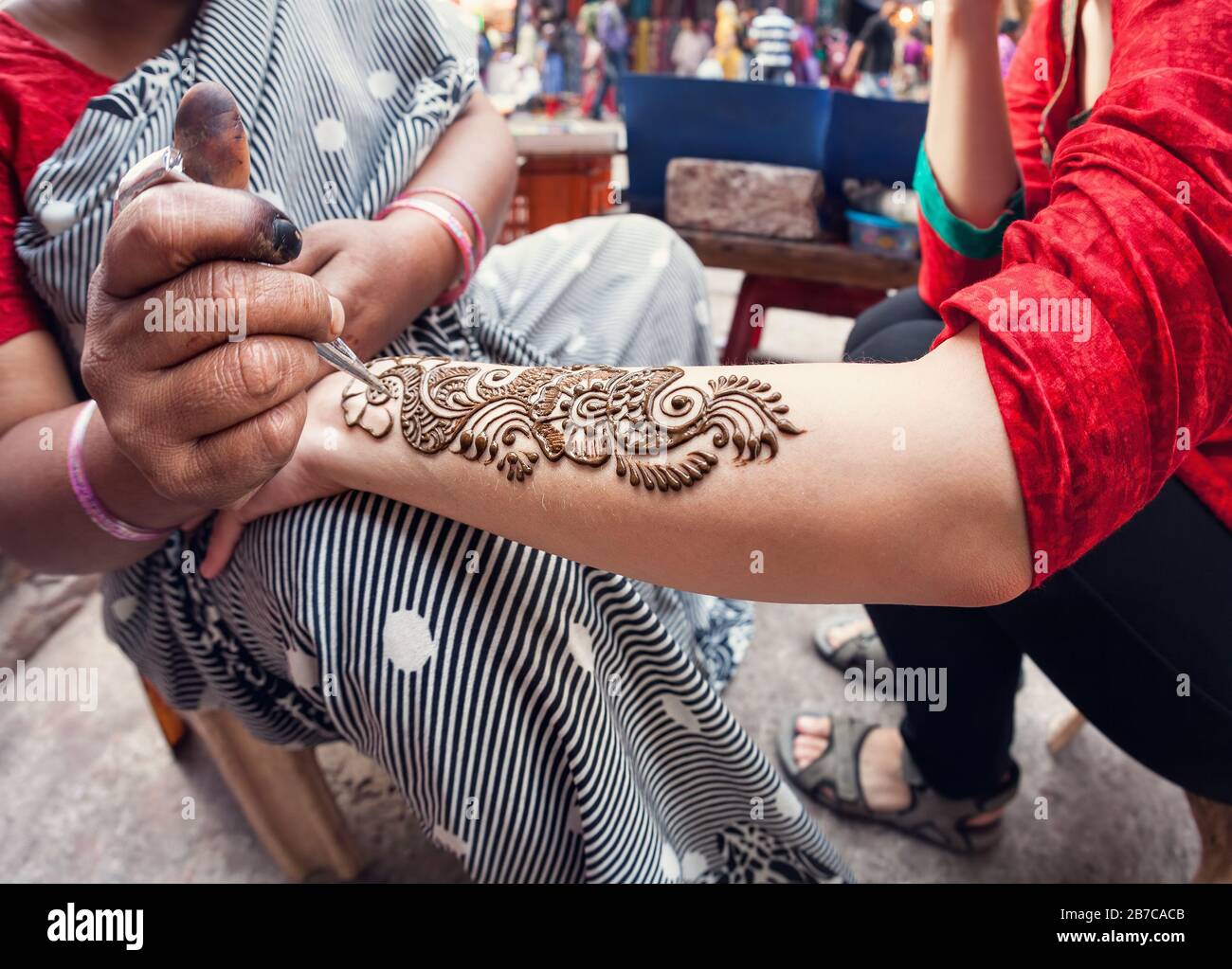 Indische Frau, die Henna auf touristischer Seite in der Hauptbasarstraße in Delhi malt Stockfoto