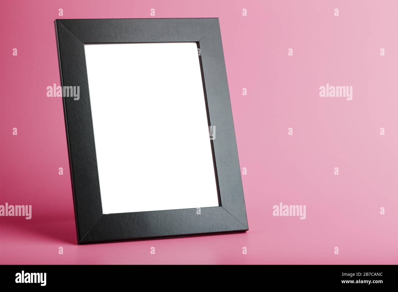 Schwarzer Bilderrahmen mit leerem Raum auf pinkfarbenem Hintergrund. Stockfoto