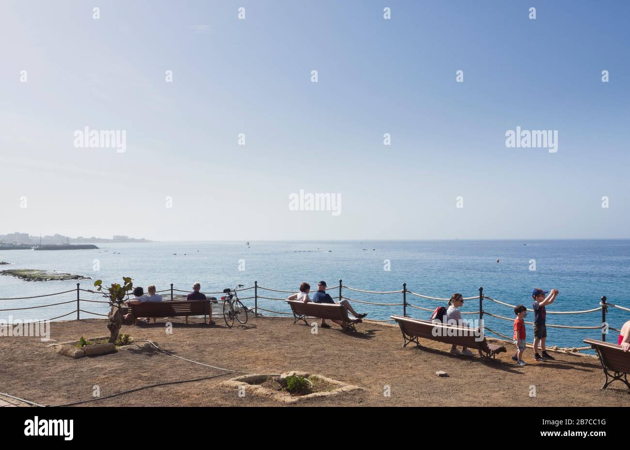 Urlauber auf Teneras, Kanarischen Inseln, Spanien, genießen einen weiteren sonnigen Tag auf Bänken mit Blick auf den Atlantik in Costa Adeje Stockfoto