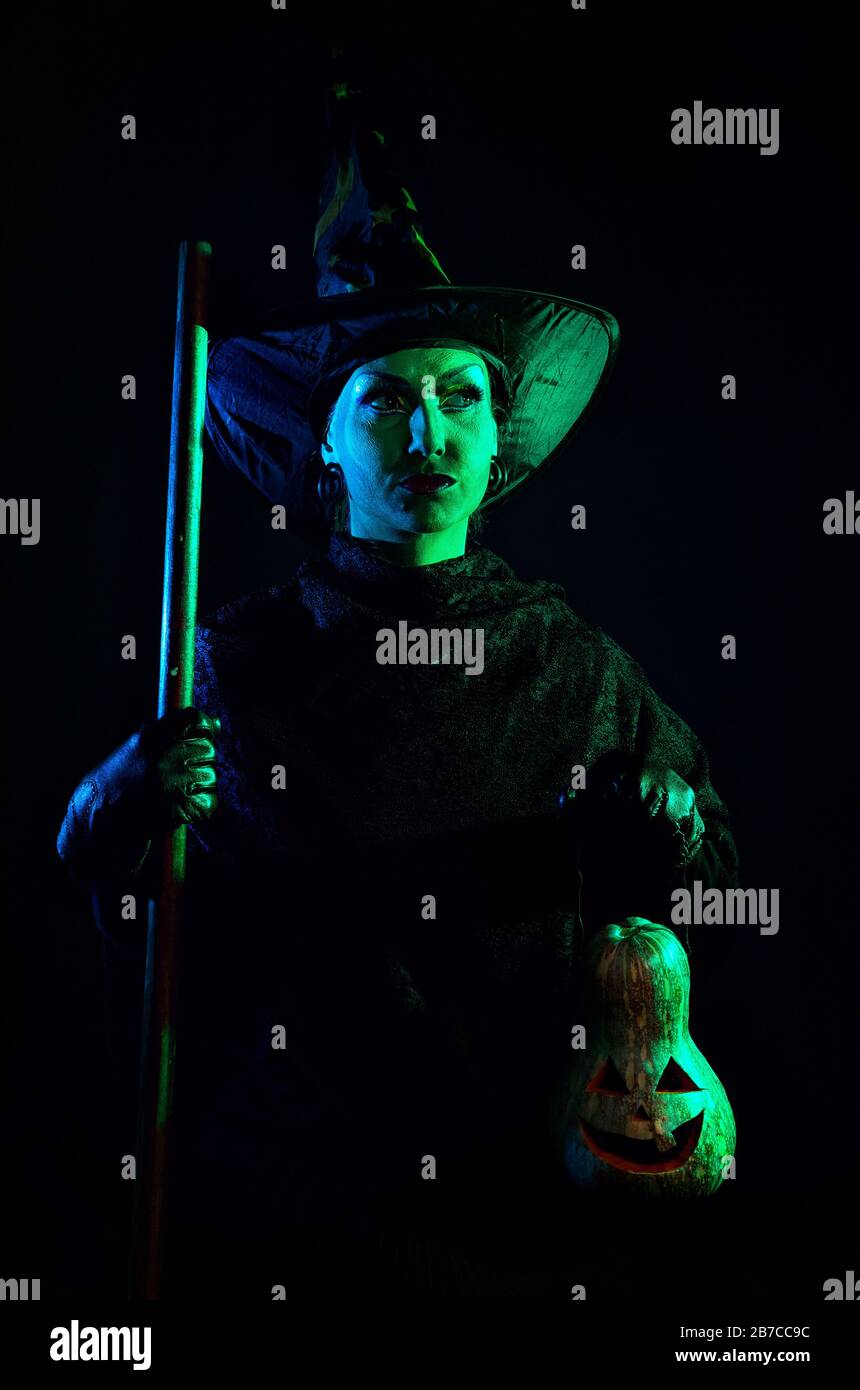 Hexe mit grüner Haut Holding geschnitzten Halloween Kürbis Laterne an dunklen Hintergrund Stockfoto