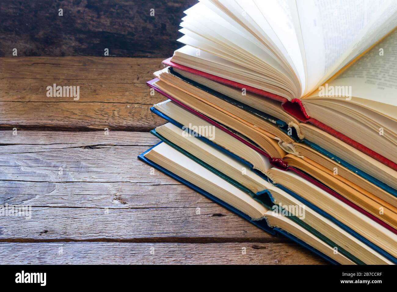 Stapel offener Bücher auf Holzhintergrund und Platz für Text Stockfoto