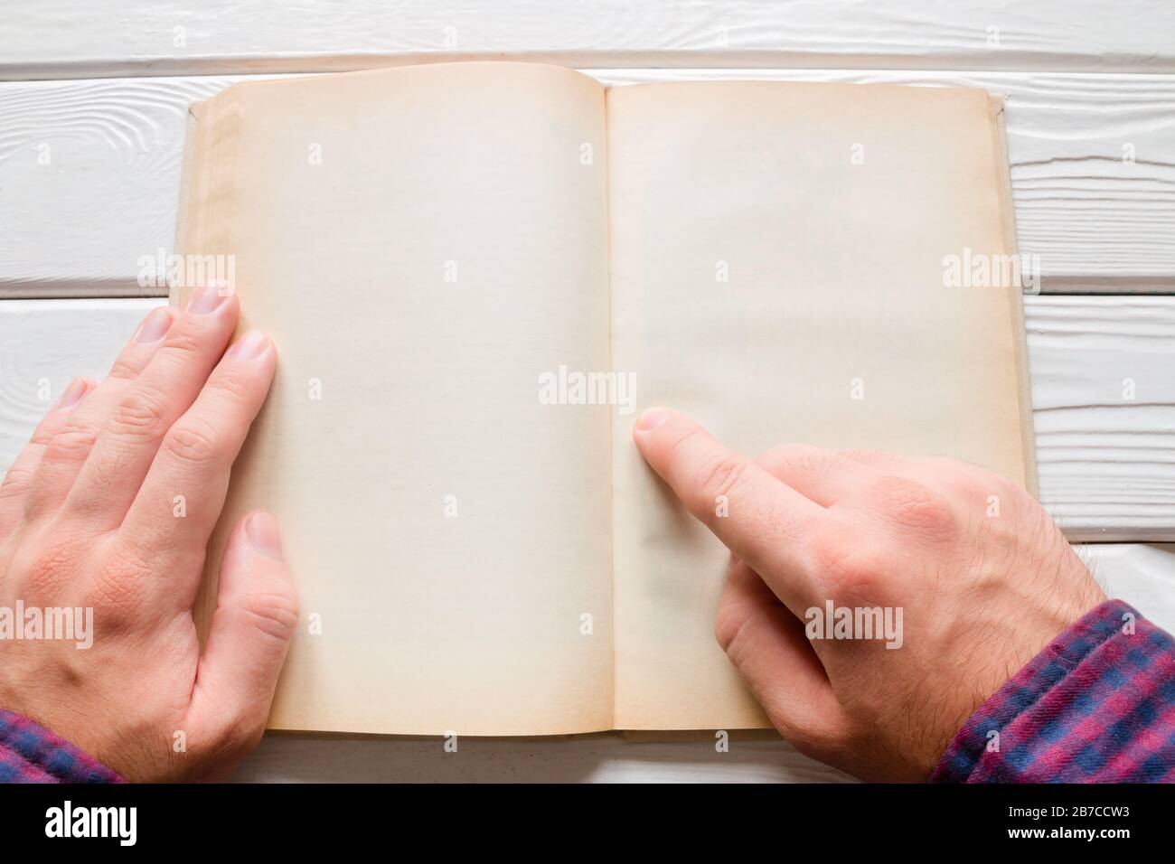 Mann liest ein Buch auf weißem Holzhintergrund Stockfoto