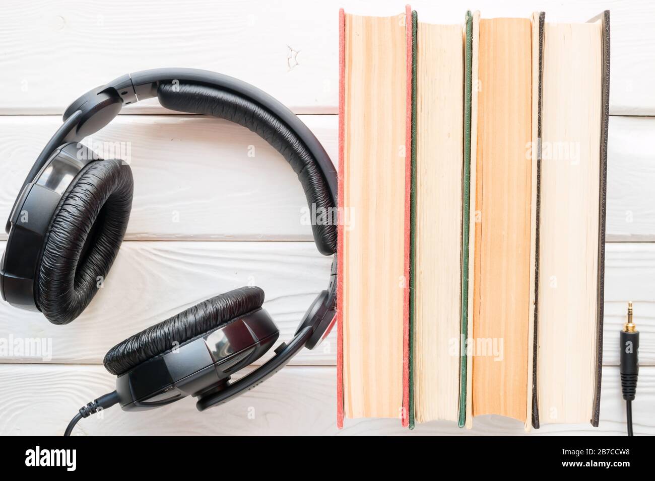 Kopfhörer neben den alten Büchern auf weißem Holzhintergrund Stockfoto