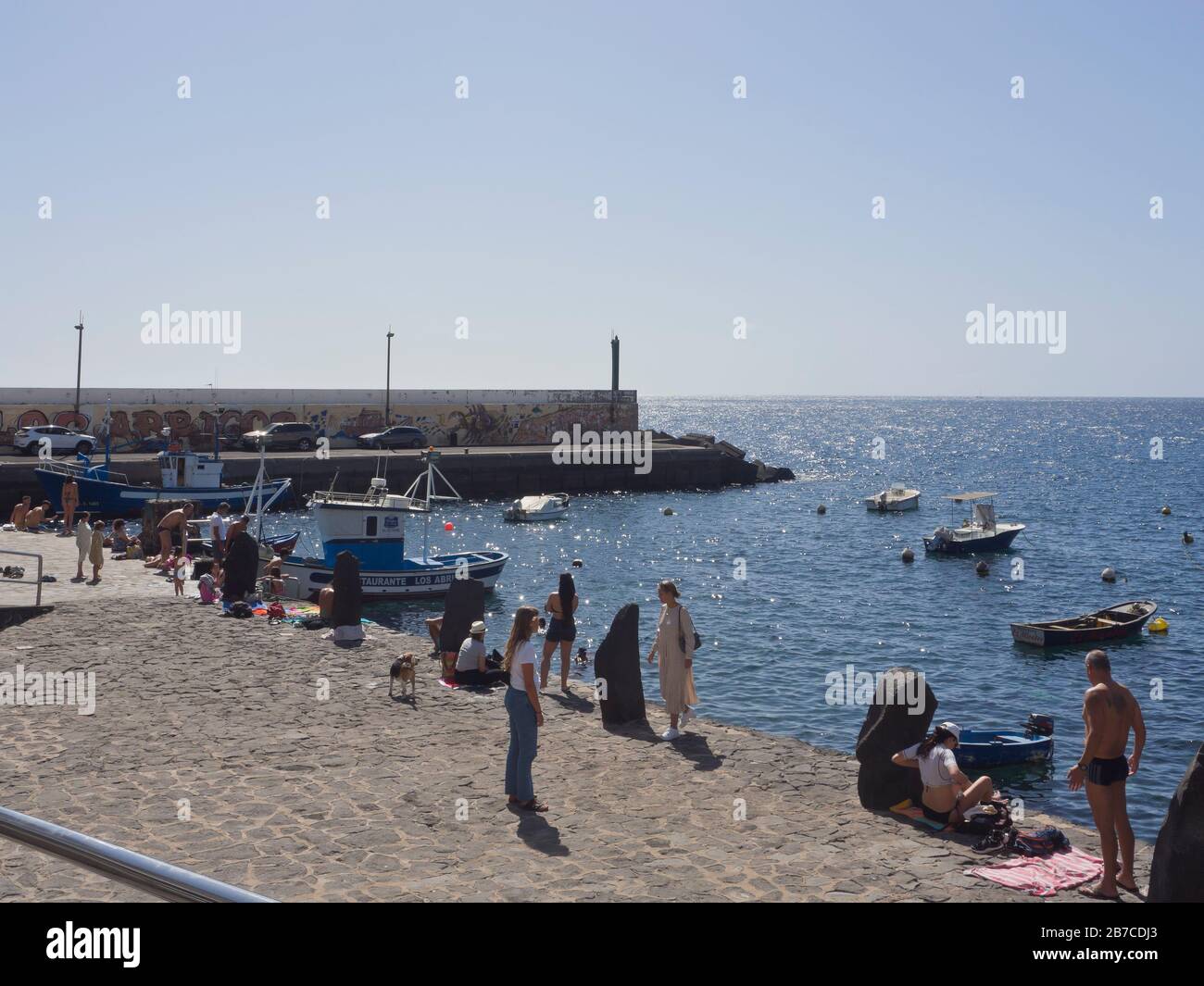 Im Fischerdorf und Hafen von Los Abrigos auf den Kanarischen Inseln auf der Insel Tenera genießen Spanien Touristen das Meer und die Sonne, die vom Wellenbrecher geschützt sind Stockfoto