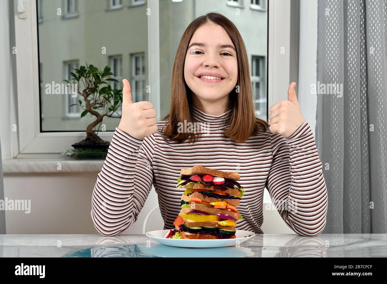 Glückliches Mädchen mit Daumen nach oben und veganes Sandwich Stockfoto