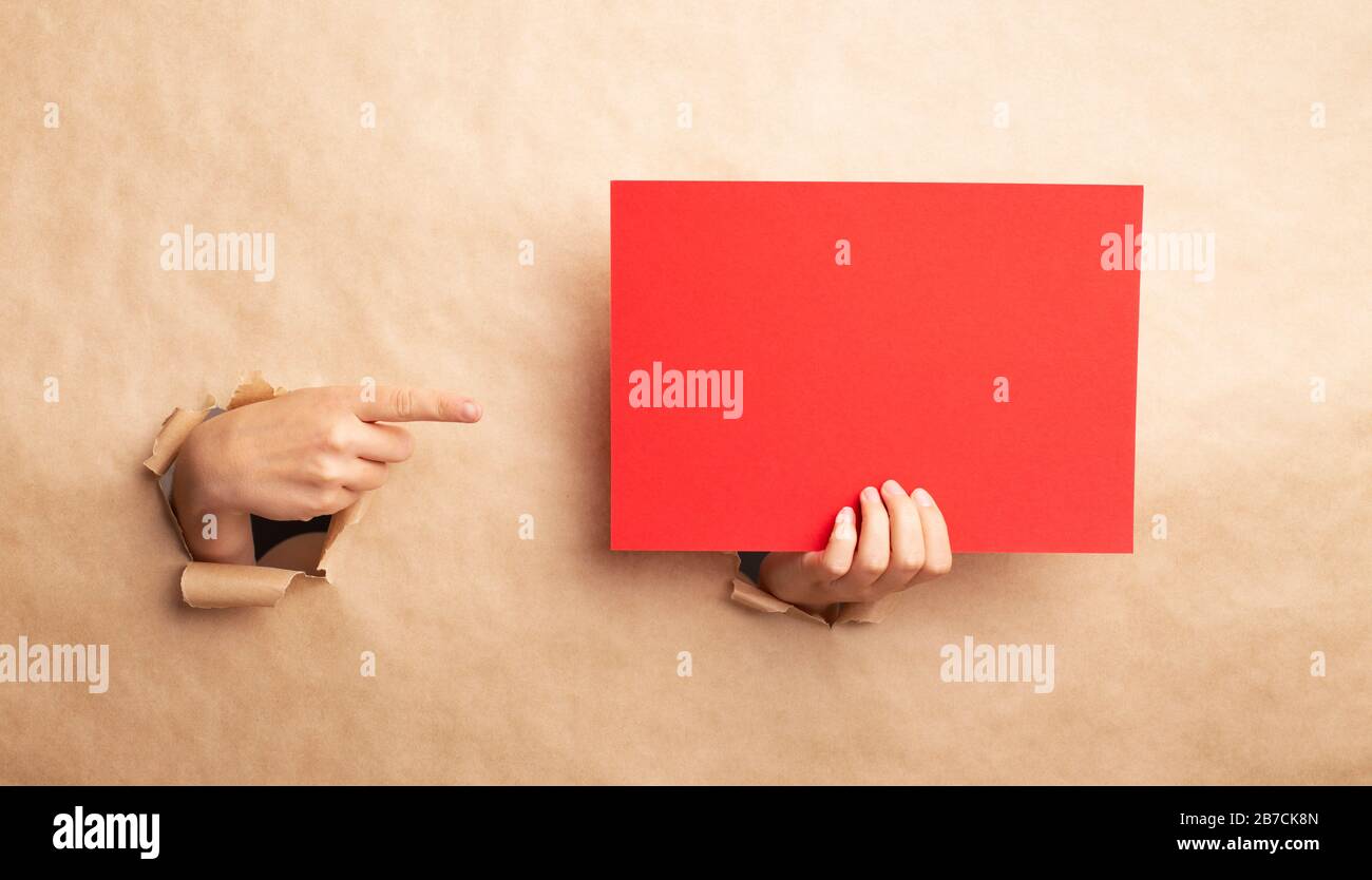 Dame, die durch die Lücke im Kraftpapier auf leeres rotes Blatt zeigt, kein Platz für das Design Stockfoto