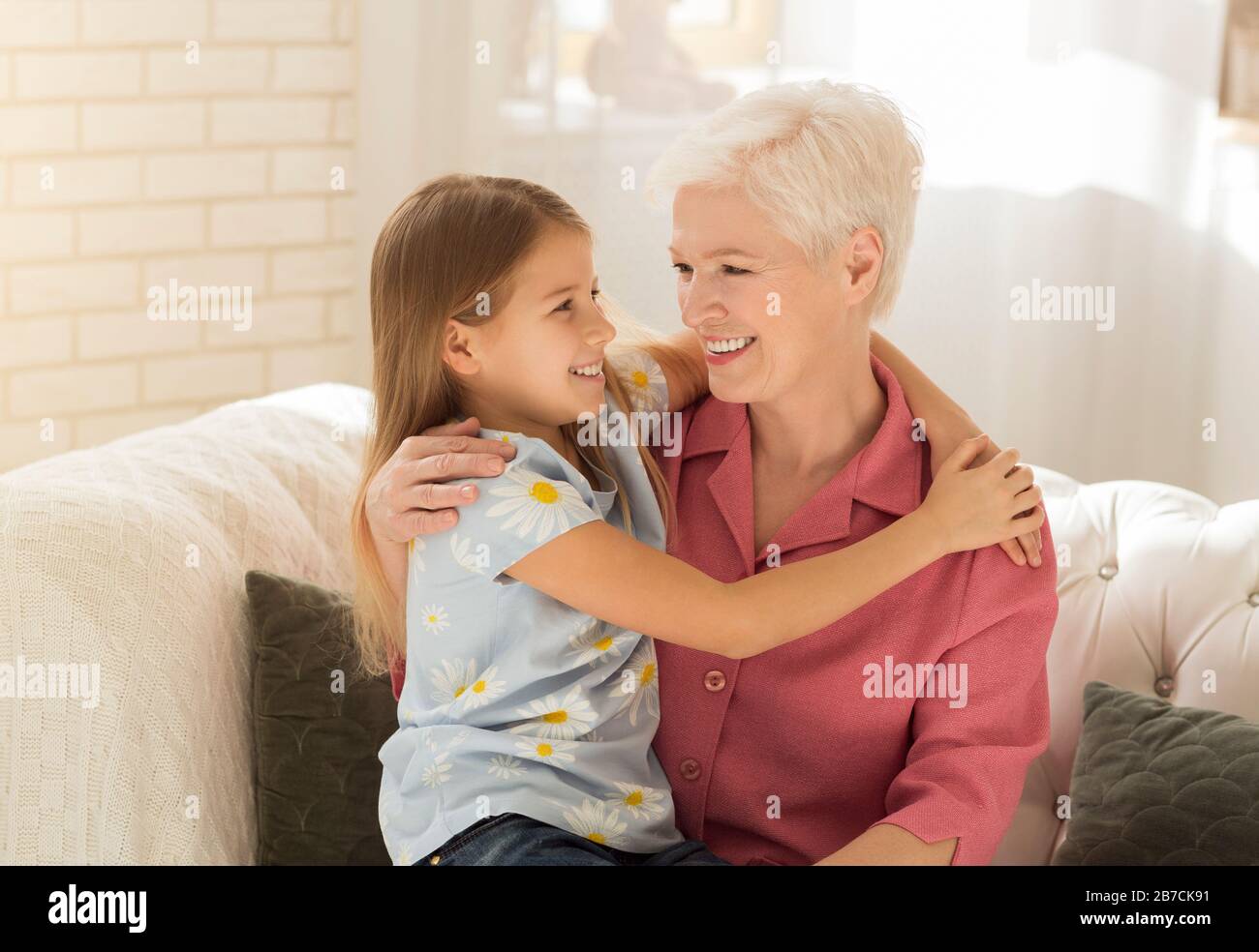 Ältere Frau mit ihrem Enkelkind umarmt zu Hause Stockfoto