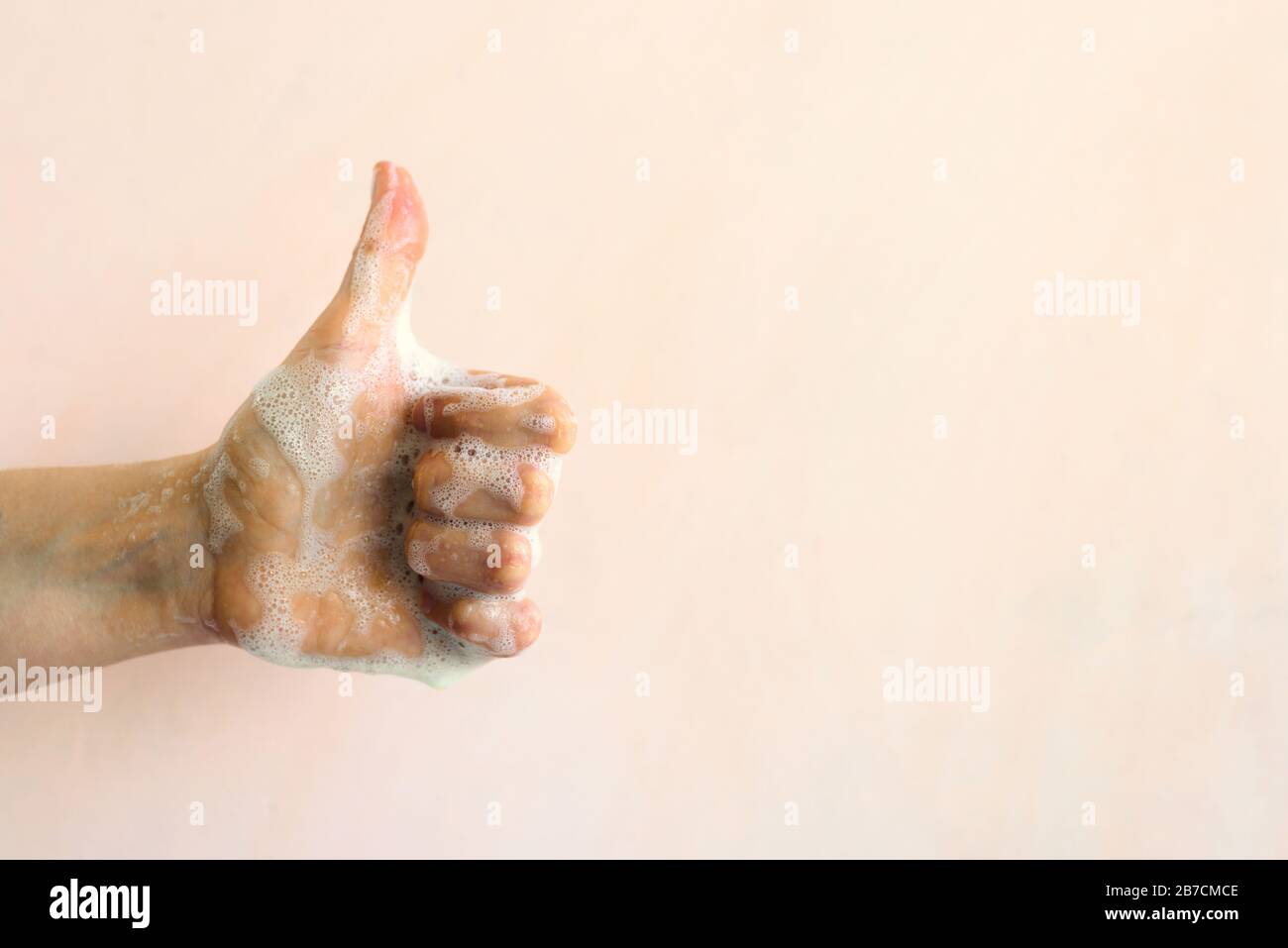 Hände mit Seifenschaum waschen. Persönliches Hygienekonzept. Daumenbewegung nach oben Stockfoto