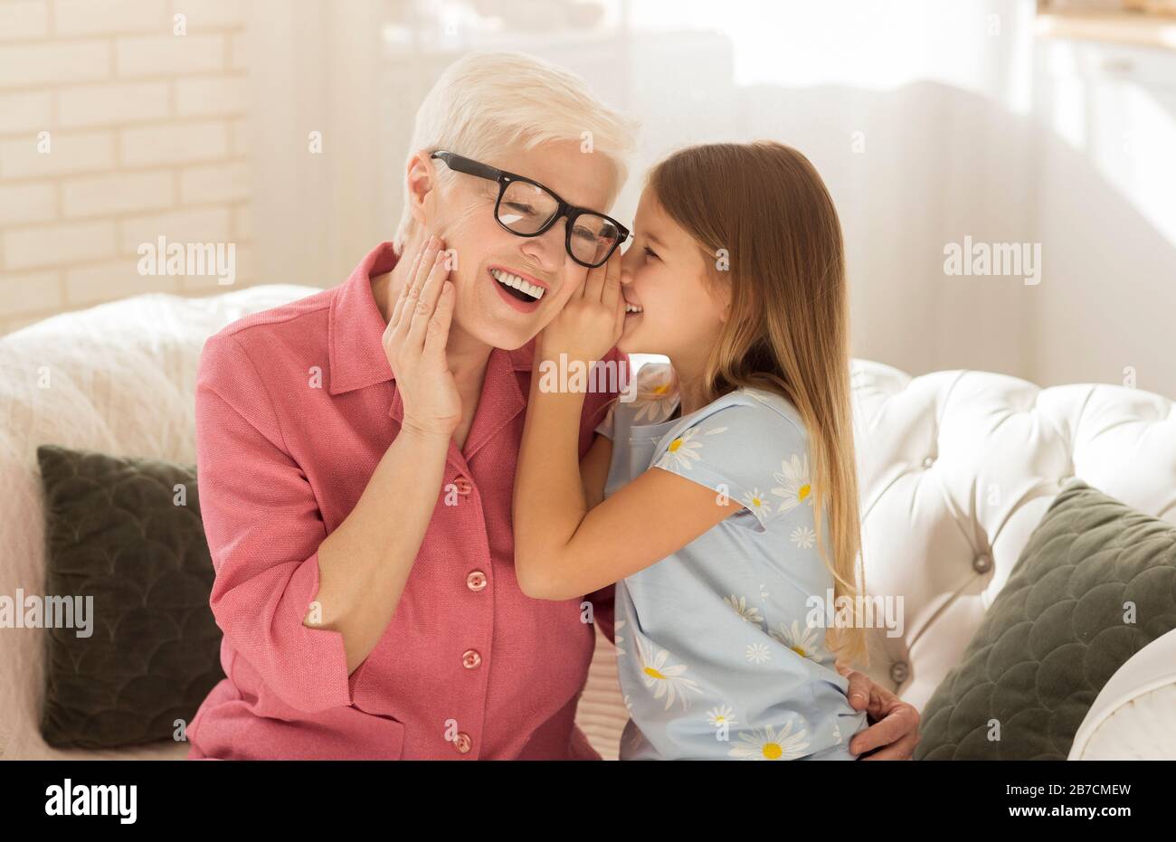 Kleines Mädchen, das zu Hause Geheimnisse mit ihrem Kindermädchen teilt Stockfoto