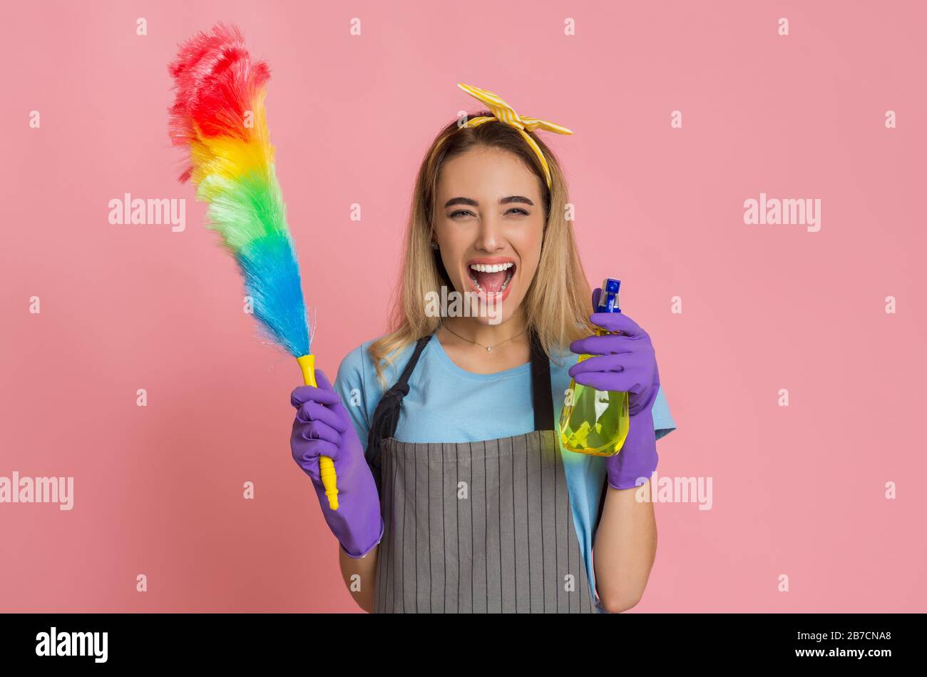 Glückliche Hausfrau mit Spray reinigt zu Hause Stockfoto