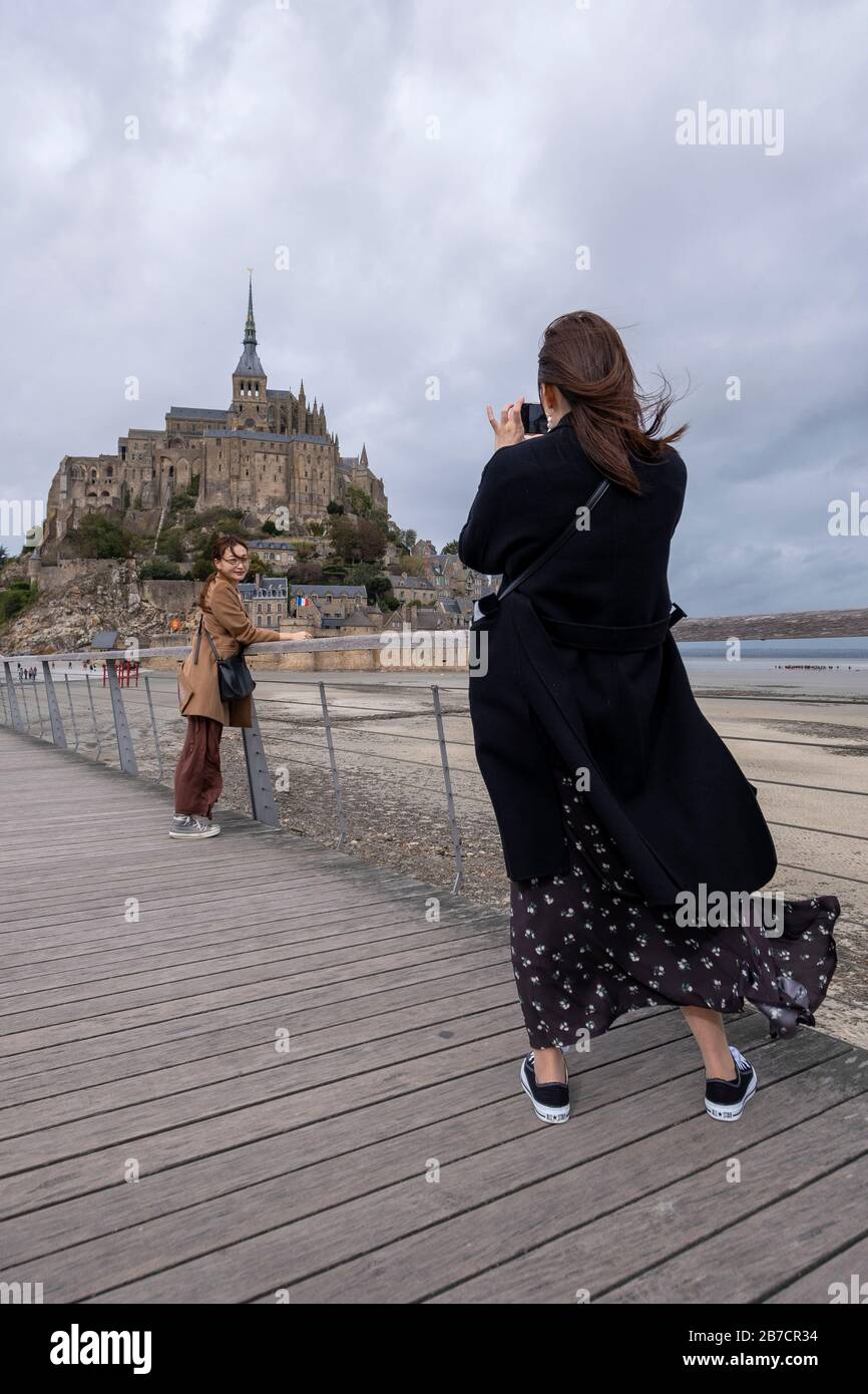 Asiatischer Tourist fotografiert einen Freund vor dem Mont-Saint-Michel, Normandie, Frankreich, Europa Stockfoto