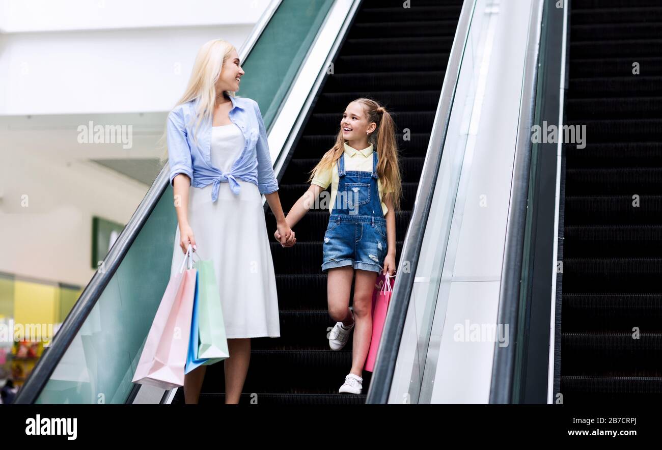 Mutter Und Tochter Ziehen Sich In Mall Die Escalator-Treppe Hinunter Stockfoto
