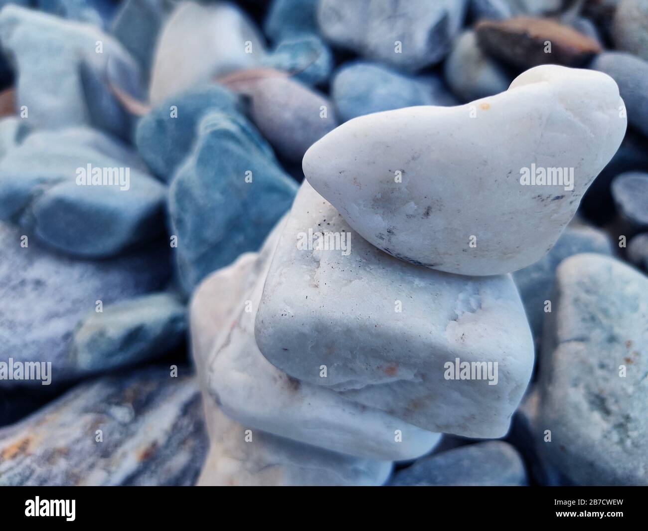 Stapel von Dreieckssteinen.Gruppe weißer und bunter Steine.Kieselturm an der Steinküste.Stones Pyramide am Kieselstrand symbolisiert Stabilität, Stockfoto