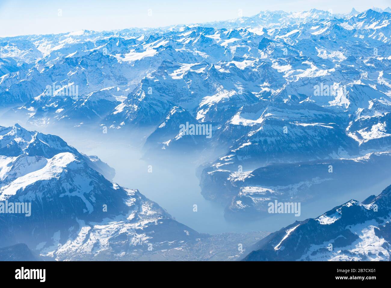 Einzigartiges alpines Luftpanorama. Blauer Planet Erde Höhenflug von einem Flugkabinenfenster aus, das über Zürich fliegt, aus dem Blick auf die Schweizer Alpen Stockfoto