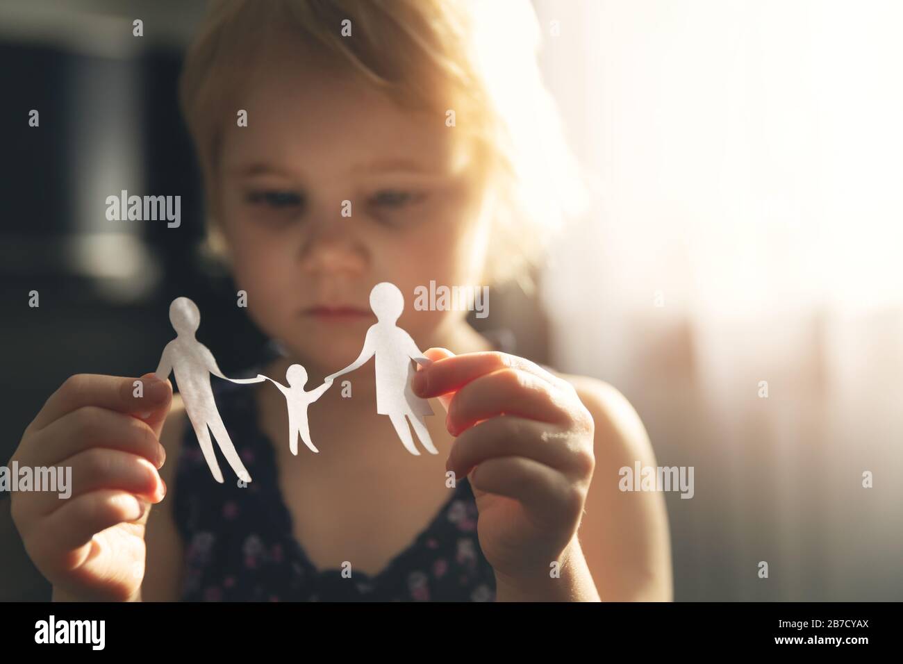 Kleines Mädchen mit Papierfamilie in Händen, Scheidungs-, Sorgerecht- und Kindesmissbrauch Stockfoto