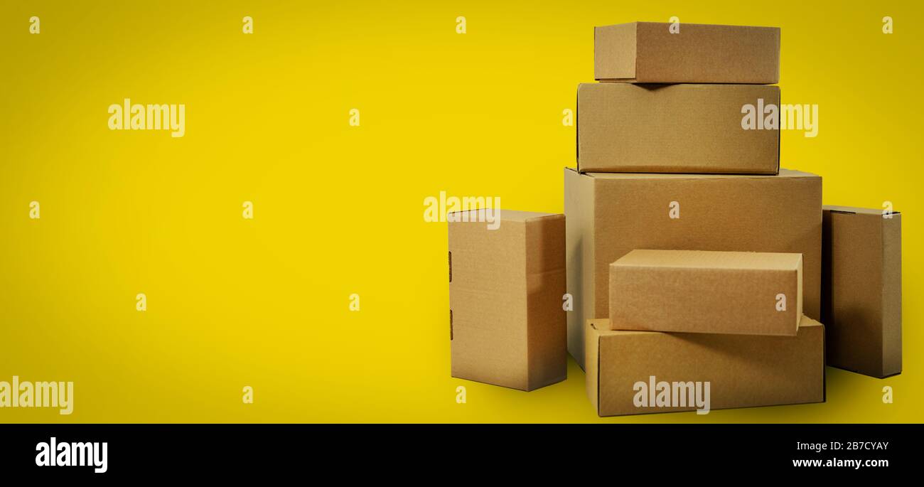 Versand und Lieferung - leere Pappkartons auf gelbem Hintergrund mit Kopierraum Stockfoto