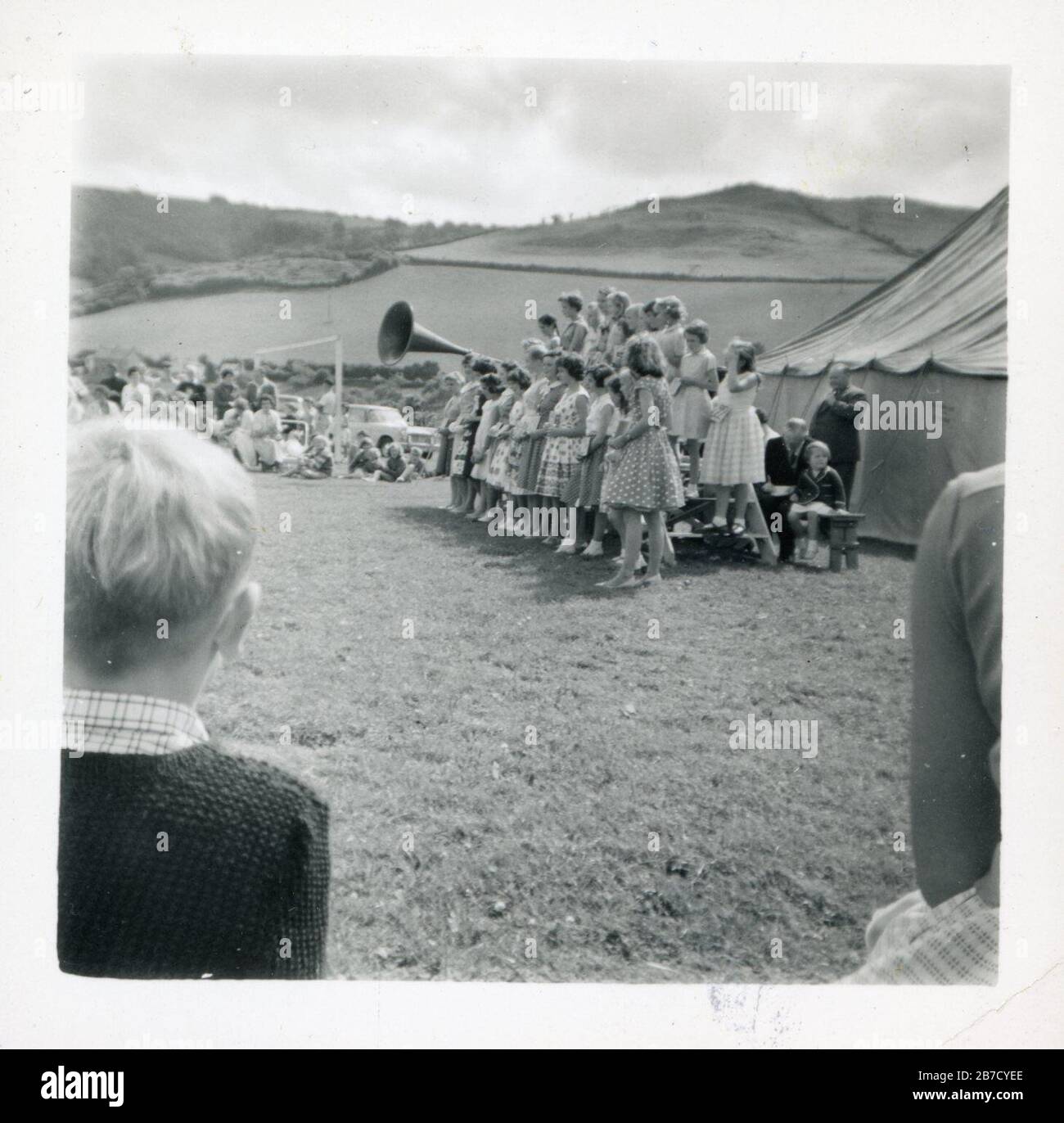 Archiv Momentaufnahme Foto c50s, es sieht aus wie eine Art Landdorf fete oder landwirtschaftliche Show mit vielleicht einem Chor auf einer behelfsmäßigen Bühne auftreten, die an die Menge durch einen großen Horn förmigen Lautsprecher ein bisschen wie ein riesiges Grammophon Horn gesendet Stockfoto