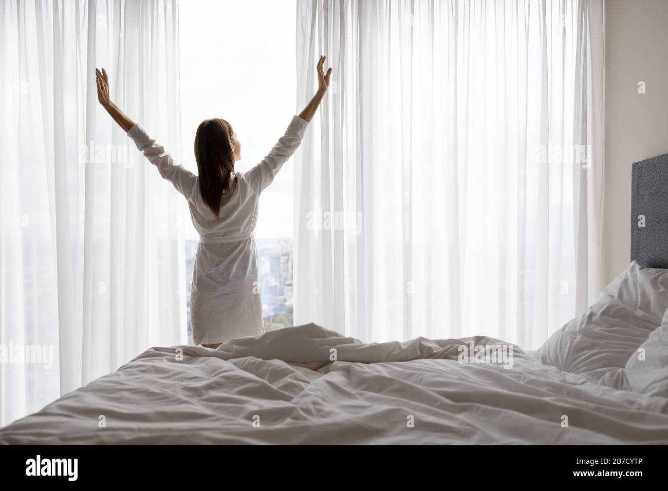 Junge Frau in der Nacht streckt Muskeln in der Nähe von Fenster. Stockfoto